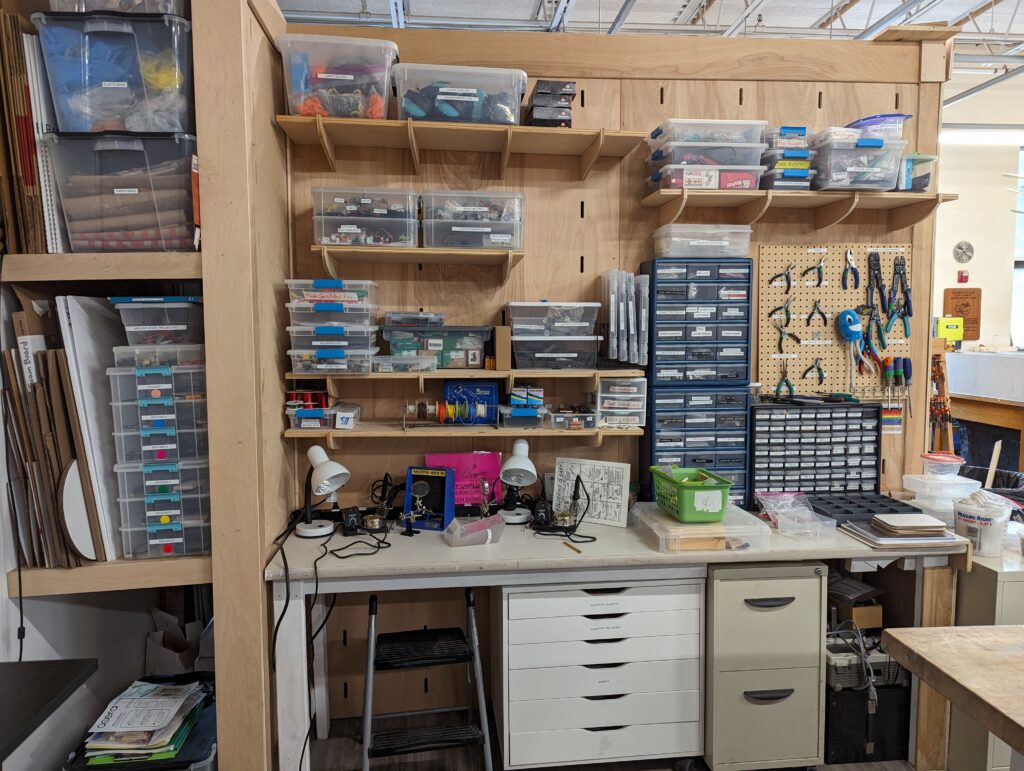 A wall in the Acera Makerspace, lined with shelves of electronics equipment and soldering tools.